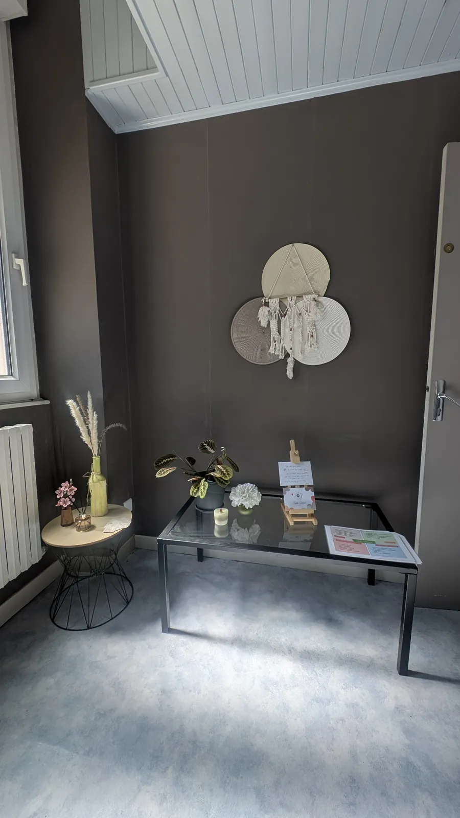 L’entrée du cabinet, avec une suspension tressée au mur et une table basse en verre
